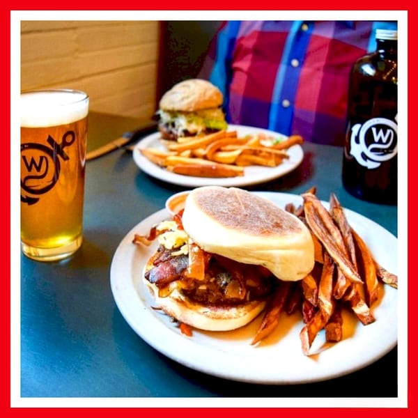 Two Crazy Burger meals with fries and drinks on a blue table, one in focus.