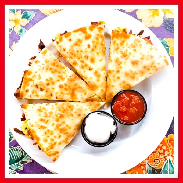 Four quesadilla slices with melted cheese, served with salsa and sour cream on a white plate.