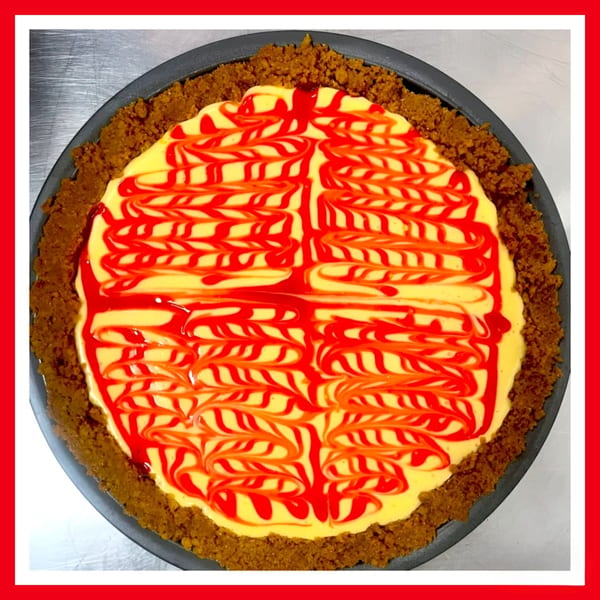 A Crazy Burger cheesecake with a graham cracker crust and red swirl topping.
