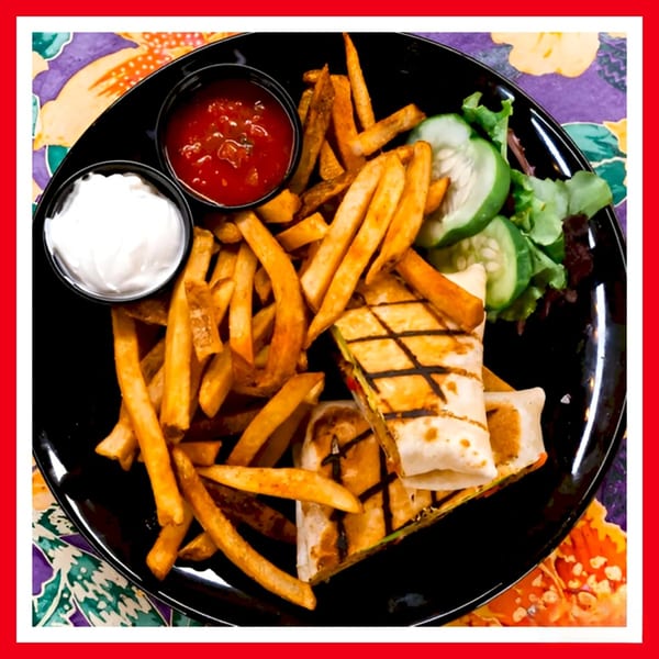 Grilled chicken wraps with fries, salsa, sour cream, and a side salad on a black plate.