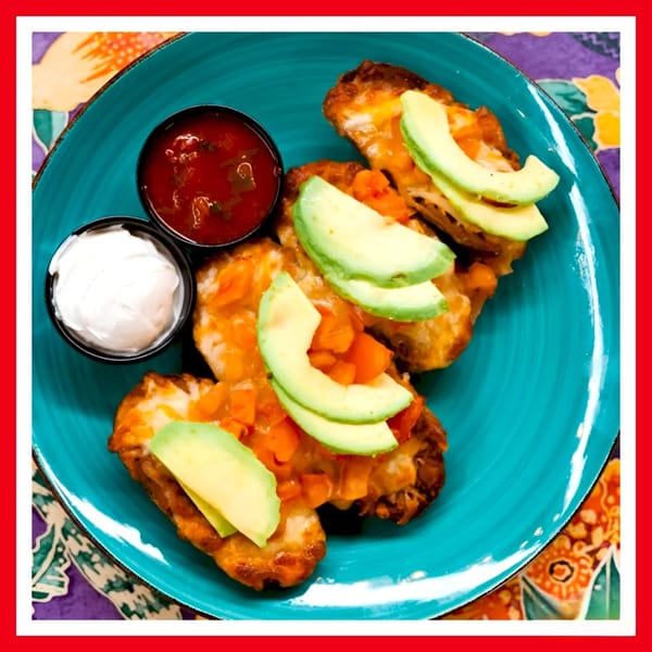 Three Crazy Burger chicken wings topped with avocado, salsa, and sour cream on a blue plate.